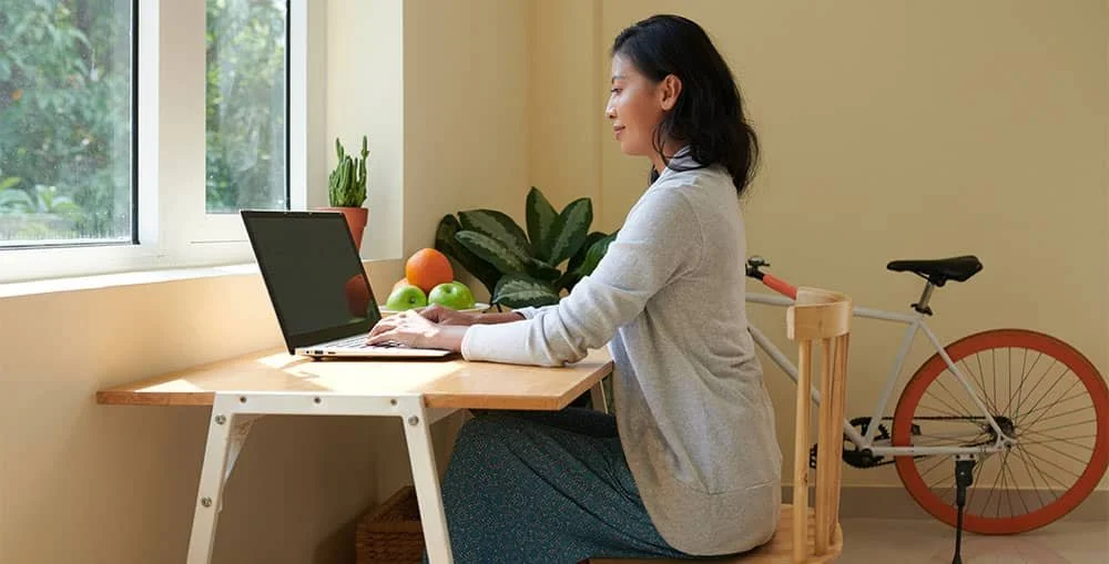 Side view of proper seated desk posture with feet flat, lumbar support, and neutral spine alignment